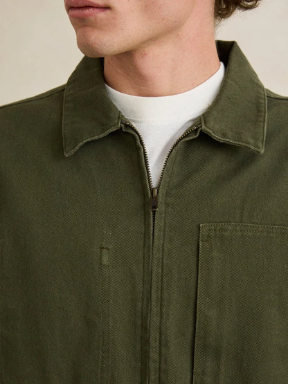 Close-up of a person wearing an olive green jacket with a white shirt underneath.