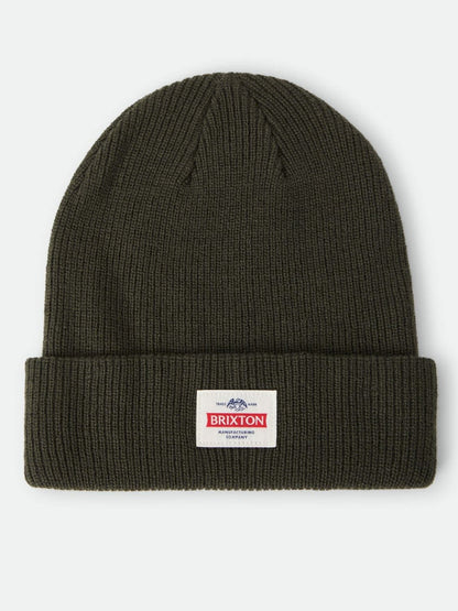 An olive green ribbed knit beanie hat with a folded cuff, featuring a small white rectangular Brixton logo patch on the front, set against a plain light gray background.