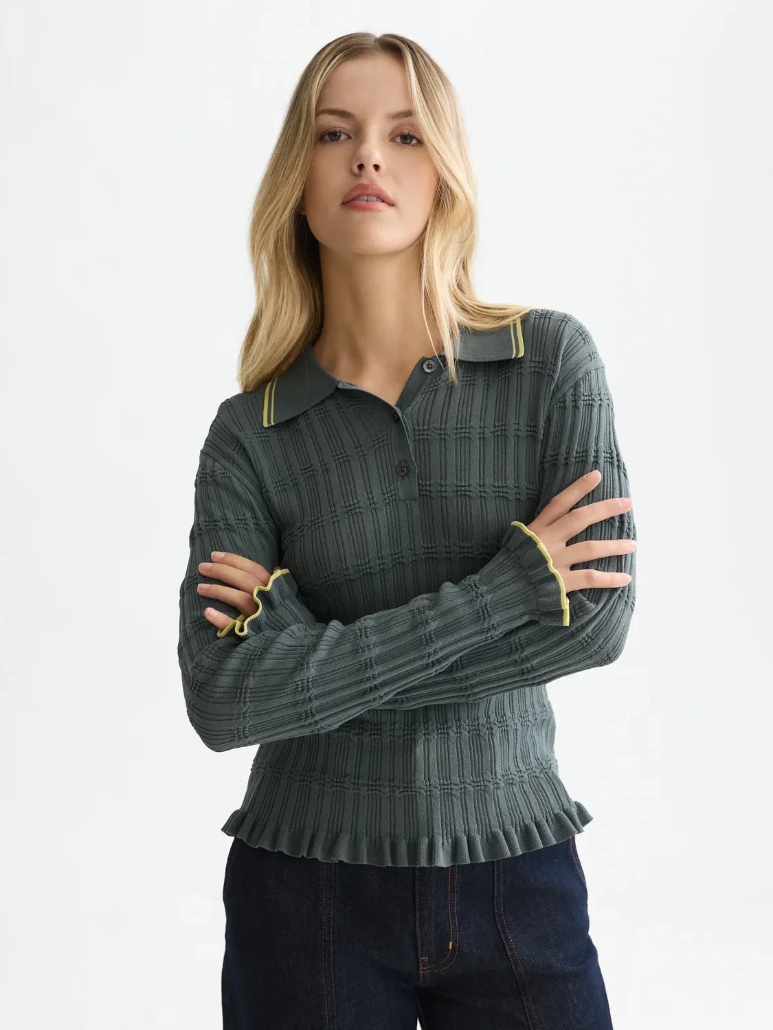 Woman wearing a green polo with yellow trim on a white background