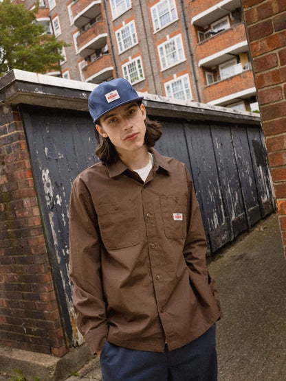 TRADEMARK SNAPBACK IN WASHED NAVY MODEL WEARING SNAPBACK HAT IN ALLEY WAY